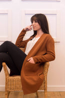 Women sits wearing Alaa Rahme Brown Cardigan
