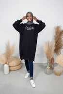 Woman wears black Feminist Sweater knee length