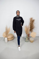 Woman wears black Feminist Sweater knee length